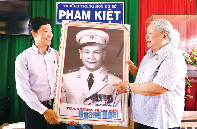 Ông Phạm Đức Hùng (bên phải) tặng ảnh chân dung Tướng Phạm Kiệt cho Trường THCS Phạm Kiệt, xã Tịnh Minh (Sơn Tịnh).