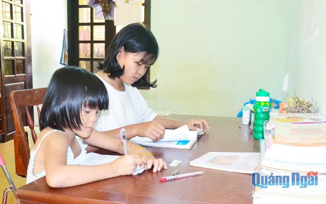  Em Đinh Thị Nhi (bên phải) thường xuyên chỉ các em nhỏ ở cùng phòng học tập.