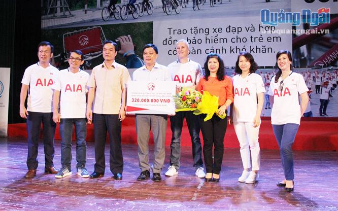 Đại diện Công ty Bảo hiểm Nhân thọ AIA Việt Nam trao bảng tượng trưng kinh phí xe đạp và hợp đồng bảo hiểm.