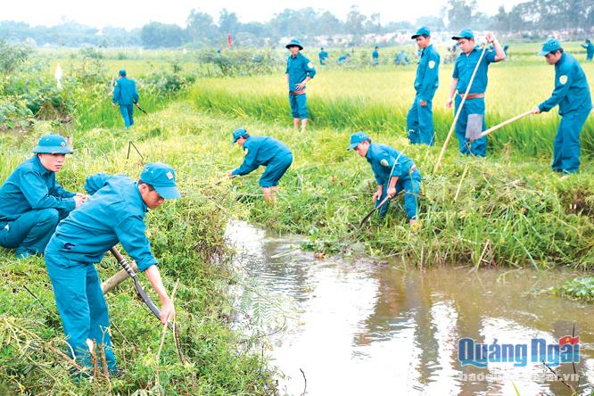 Lực lượng dân quân tự vệ huyện Sơn Tịnh giúp dân nạo vét kênh mương.