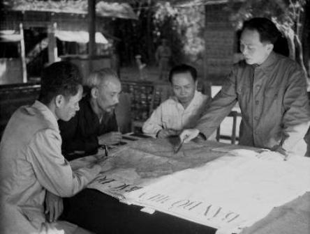Đại tướng Võ Nguyên Giáp (đứng, bên phải) trình bày với Chủ tịch Hồ Chí Minh và các đồng chí lãnh đạo Đảng, Nhà nước bàn kế hoạch mở chiến dịch Điện Biên Phủ năm 1954. Ảnh: TTXVN.