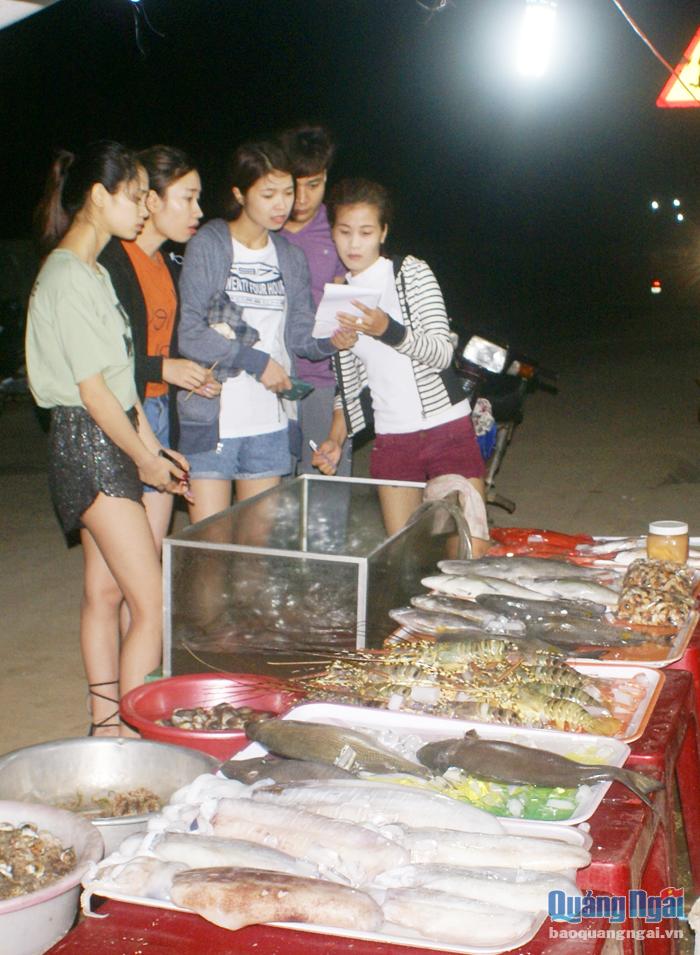 Du khách tham khảo thực đơn tại quán hải sản đêm ở Lý Sơn.