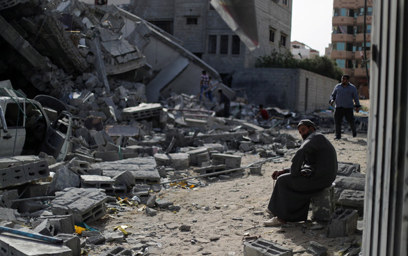  Một người đàn ông Palestine ngồi trên đống đổ nát gần một tòa nhà bị phá hủy trong các đợt không kích của Israel tại thành phố Gaza - Ảnh: REUTERS