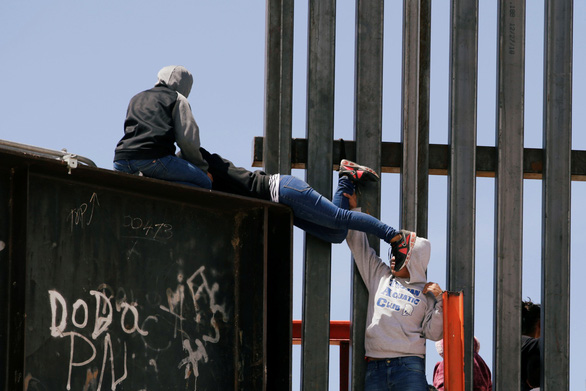  Người di cư trèo tường qua biên giới Mỹ từ phía Mexico ngày 22-6-2019 - Ảnh: REUTERS