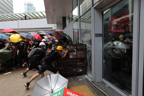  Người biểu tình dùng xe đẩy hàng để phá vỡ cửa kính tại LegCo - Ảnh: REUTERS