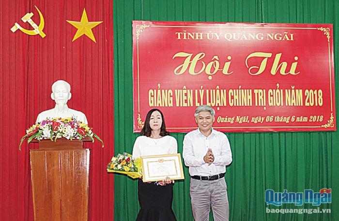  Trưởng ban Tuyên giáo Tỉnh ủy Võ Văn Hào trao giải nhất cho thí sinh Nguyễn Thị Ánh Dương tại Hội thi Giảng viên lý luận chính trị giỏi năm 2018.    ẢNH: THANH THUẬN
