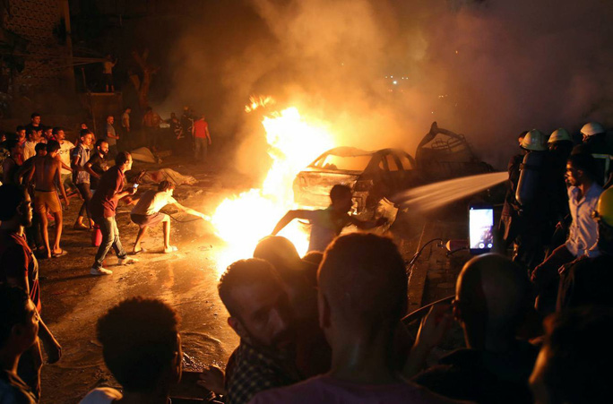  Người dân xông vào dập lửa sau vụ tai nạn xe hơi bên ngoài Viện Ung thư Quốc gia Ai Cập hôm 4-8. Ảnh: Reuters