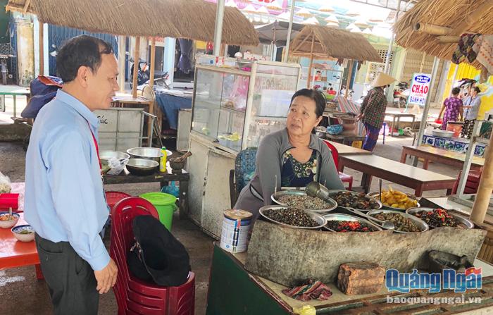Cán bộ Khoa An toàn thực phẩm, Trung tâm Y tế huyện Bình Sơn kiểm tra việc chế biến thực phẩm của tiểu thương chợ Châu Ổ.