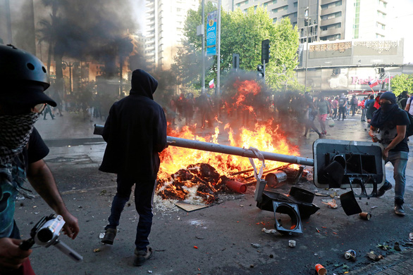 Người biểu tình đốt cột đèn giao thông trong cuộc biểu tình chống chính phủ tại Santiago, Chile ngày 29-10 - Ảnh: REUTERS
