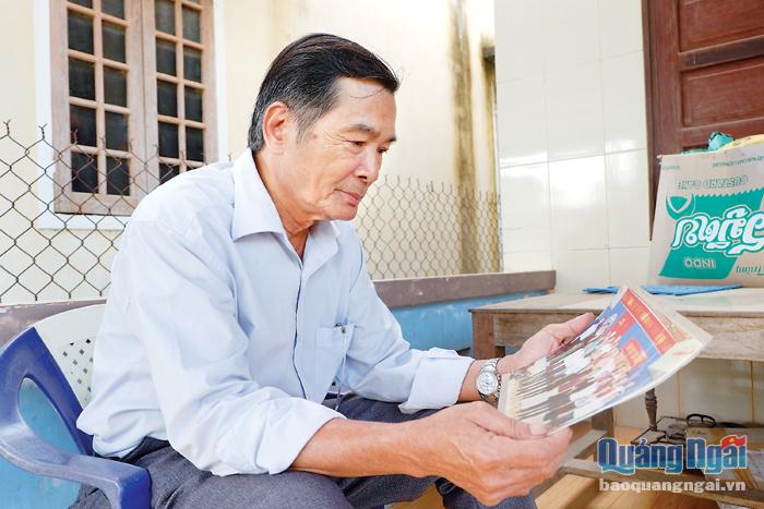 Ông Nguyễn Nhơn xem tấm hình chụp cùng với đồng đội vào dịp kỷ niệm 50 năm thành lập Đoàn Văn công giải phóng huyện Mộ Đức.