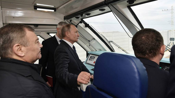 Tổng thống Putin đứng trong khoang lái đoàn tàu khai trương tuyến đường sắt nối hai thành phố với Crimea ngày 23-12 - Ảnh: REUTERS