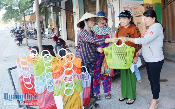 Bà Dương Thị Thế Thanh hỗ trợ phụ nữ ở phường Trương Quang Trọng (TP.Quảng Ngãi) giỏ xách nhựa để đi chợ. 
