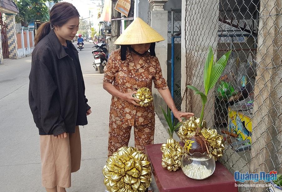 Cô sinh viên khéo tay Dương Thị Thúy Hồng cùng quầy bán dừa nước sơn màu giản dị của mình tại thôn Kỳ Xuyên, xã Tịnh Kỳ