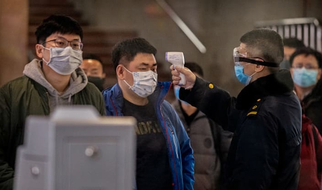 Kiểm tra thân nhiệt hành khách trên tàu từ Vũ Hán tới Bắc Kinh ngày 23-1. Ảnh: Getty Images