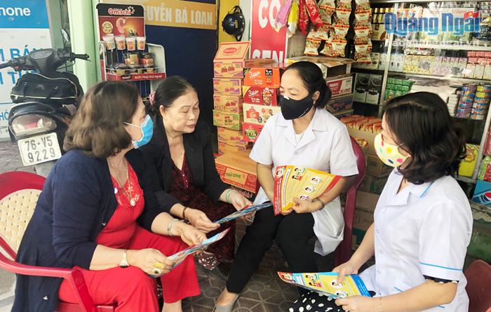 Cán bộ y tế phường Trần Hưng Đạo hướng dẫn biện pháp phòng, chống dịch Covid-19 cho các tiểu thương ở chợ Quảng Ngãi.