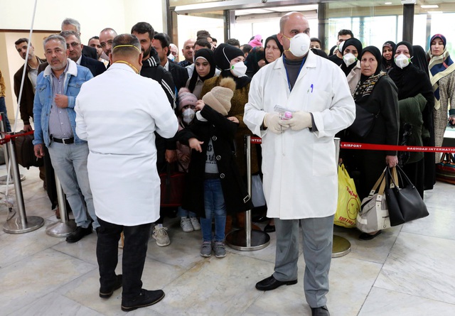 Các nhân viên y tế kiểm tra nhiệt độ của các hành khách đến sân bay Baghdad, Iraq. (Ảnh: EPA)