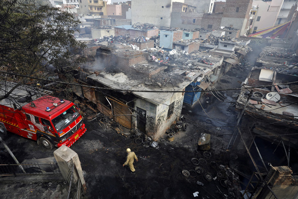 Nhân viên cứu hỏa tại hiện trường một cửa hàng bán lốp xe bị phóng hỏa cháy rụi do xung đột giữa người ủng hộ và phản đối luật quốc tịch mới ở New Delhi - Ảnh: REUTERS