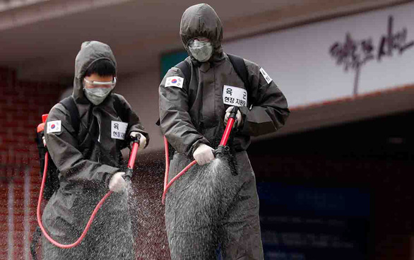 Binh sĩ Hàn Quốc phun thuốc tẩy trùng ở khu nhà tại Daegu ngày 9-3 - Ảnh: Reuters