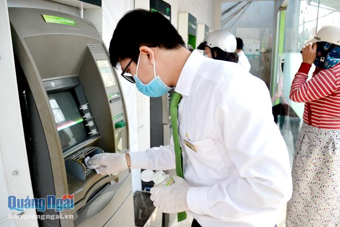 Nhân viên bộ phận tiếp quỹ của Vietcombank Quảng Ngãi làm vệ sinh bằng dung dịch sát khuẩn tại các trụ ATM. Ảnh: H.Hoa