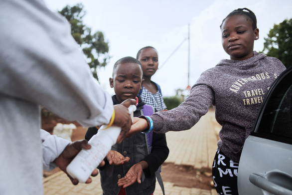 Nhân viên Chữ thập đỏ quốc tế xịt nước rửa tay cho một người dân Nam Phi - Ảnh: AFP
