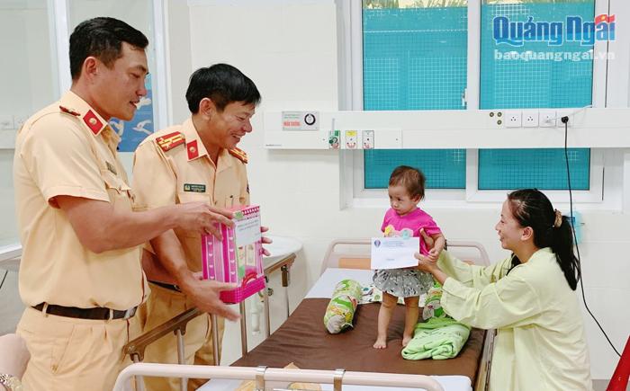 Cán bộ, chiến sĩ Phòng Cảnh sát giao thông trao quà cho mẹ con một bệnh nhân nhi.     Ảnh: PV