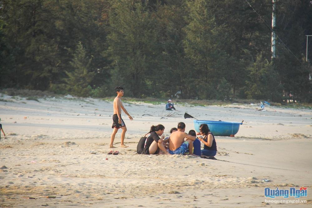 Nhiều gia đình mang theo con nhỏ, ngồi ăn uống trên bãi cát