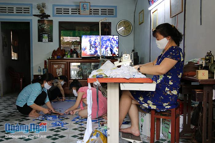 Bà Hồ Thị Thu (ngồi bên máy may) cùng hai hội viên Chi hội phụ nữ đang miệt mài với công việc may khẩu trang miễn phí