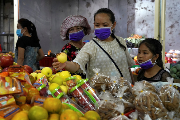 Người dân đeo khẩu trang mua trái cây trong một khu chợ ở Phnom Penh - Ảnh: REUTERS