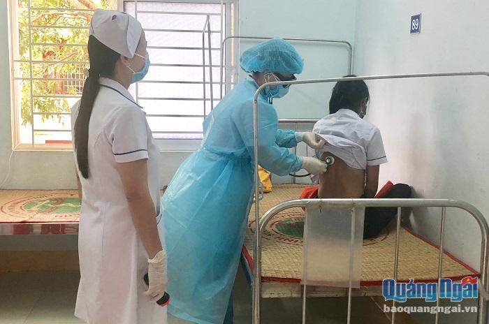 Nhân viên y tế Trung tâm Y tế huyện Bình Sơn kiểm tra sức khỏe cho một trường hợp có dấu hiệu ho, sốt