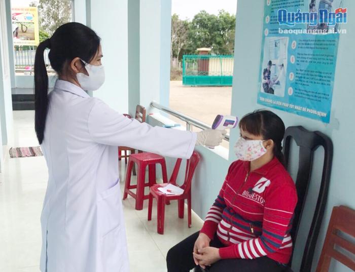 Nhân viên Trạm Y tế xã Tịnh Thọ (Sơn Tịnh) kiểm tra thân nhiệt cho người dân đến khám bệnh.  Ảnh: K.Ngân 
