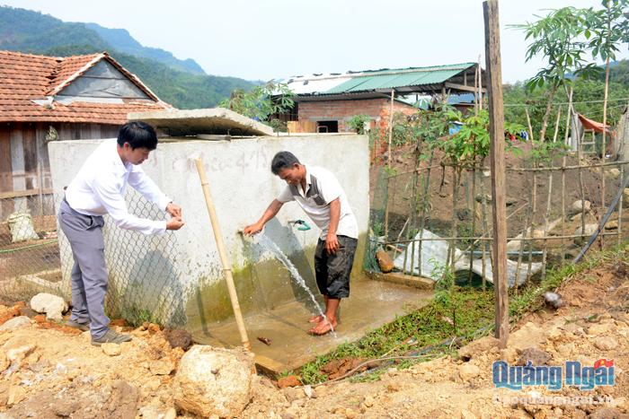 Phó Chủ tịch UBND xã Sơn Bua (Sơn Tây) Đỗ Minh Vương (bên trái) hướng dẫn thanh niên địa phương sử dụng, bảo quản công trình nước sạch.