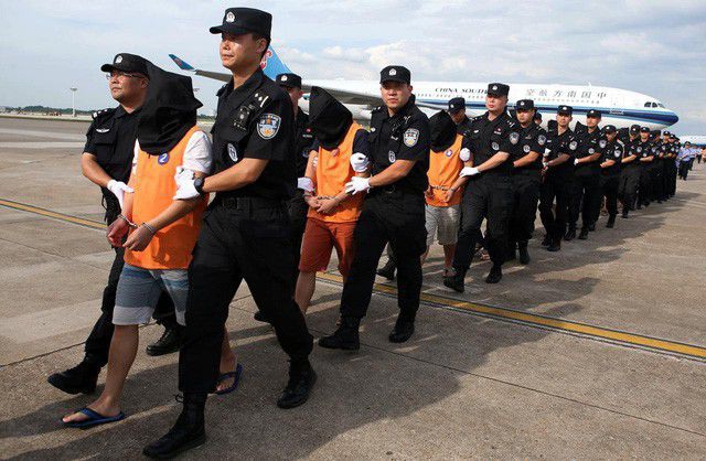 Cảnh sát Trung Quốc áp giải các nghi phạm lừa đảo người Trung Quốc bị Campuchia trục xuất tại sân bay ở tỉnh Hồ Nam (Ảnh: Reuters)