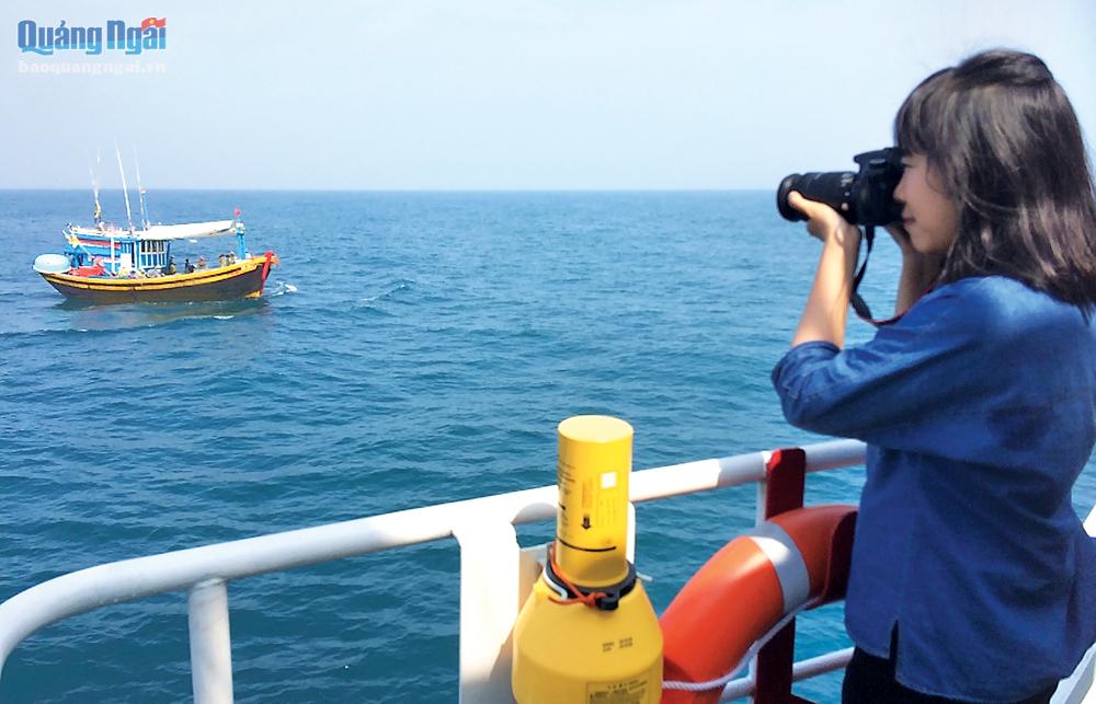 Phóng viên Ý Thu chụp ảnh ngư dân khai thác hải sản trên biển.