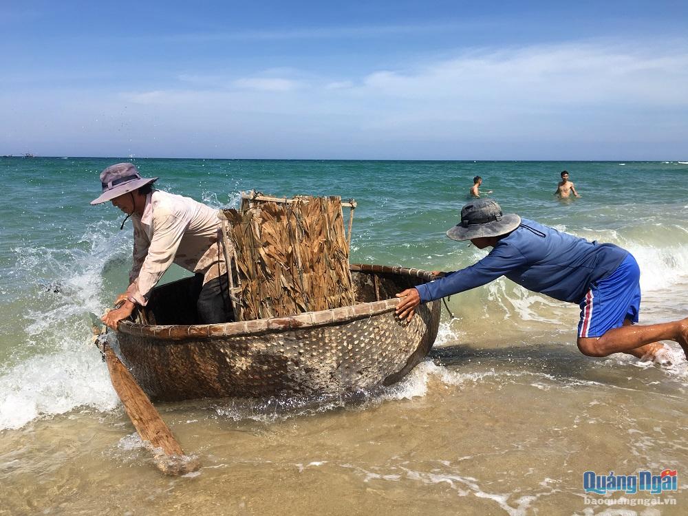 . Ngư dân Lê Văn Tám hì hục đẩy chiếc thúng chai băng qua bãi cát xuống mép biển