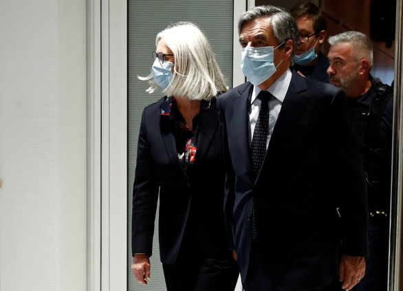 Vợ chồng cựu thủ tướng Pháp François Fillon đeo khẩu trang khi rời phiên tòa ở Paris ngày 29-6 - Ảnh: REUTERS