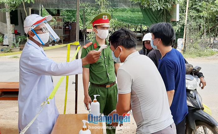 Nhân viên y tế đo thân nhiệt người dân tại chốt kiểm tra xã Sơn Hạ (Sơn Hà).           Ảnh: B.Sơn