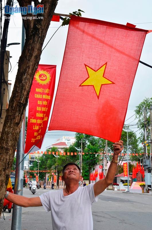 Người dân treo cờ Tổ quốc chào mừng đại hội trên đường Lê Trung Đình.