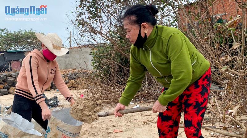 Người dân tranh thủ ra bãi biển xúc cát cho vào bao để mang về nhà gia cố nhà cửa