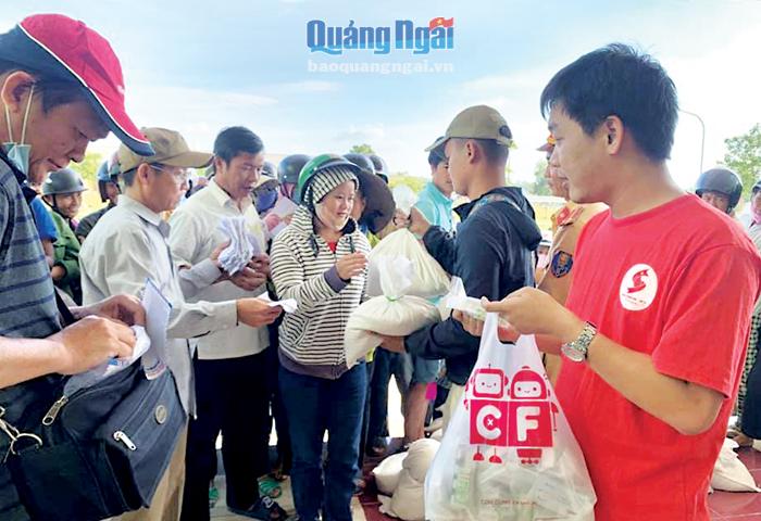 Anh Nguyễn Thanh Lời (áo đỏ) đang phát quà hỗ trợ người dân vùng lũ Quảng Trị.  Ảnh: Kim Ngân