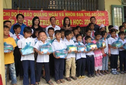 Em Phạm Minh Thắng (hàng đầu, thứ ba từ trái sang) vui mừng khi được nhận quà tặng là sách, vở và các dụng cụ học tập khác.