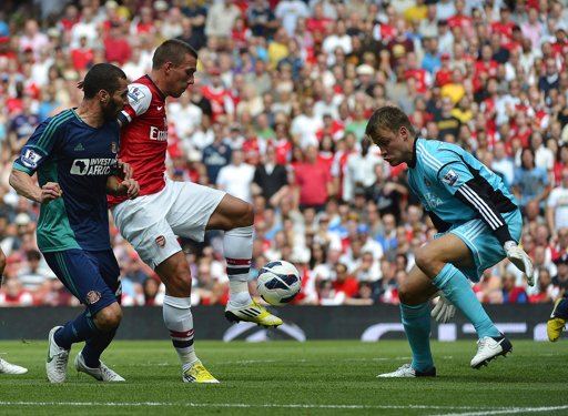 Tiền đạo Lukas Podolski (giữa) không thể thắng được thủ môn Simon Mignolet của Sunderland trong pha đối mặt. Ảnh: Reuters.