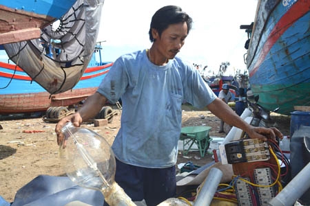 Ngư dân Huỳnh Văn Lắm rầu rĩ gỡ hệ thống đèn cao áp ra khỏi tàu để chuyển sang nghề khác.