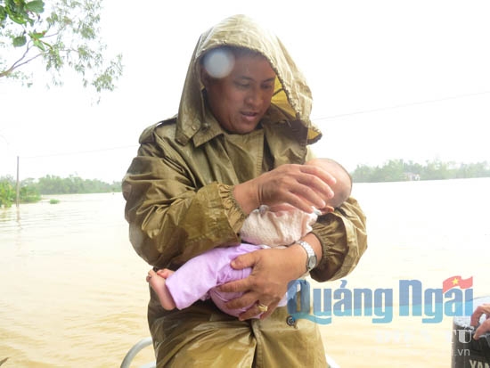 Trung úy Phạm Bá Chỉnh bế cháu bé chưa đầy 4 tháng tuổi vừa được cứu trong căn nhà ngập sâu trong nước