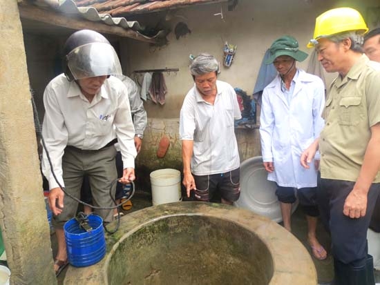 Phó Chủ tịch UBND tỉnh Lê Quang Thích (đứng thứ nhất bên phải) kiểm tra việc xử lý giếng nước bị ngập lụt tại xã Hành Minh (Nghĩa Hành).