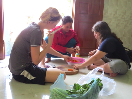 Chị Trần Thị Mến (áo đỏ) đang hướng dẫn 2 nữ sinh người Mỹ chế biến món ăn Việt