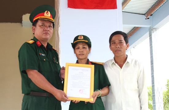 Đại tá Trần Xi Noa - Phó Chính ủy trao quyết định nhà tình nghĩa cho quân nhân Nguyễn Thị Tú, Ban CHQS huyện Minh Long.