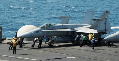 Các thủy thủ trên tàu sân bay USS George H.W. Bush (Mỹ) đang hỗ trợ một chiến đấu cơ F/A-18C Hornet đậu trên bong tàu - Ảnh: Reuters
