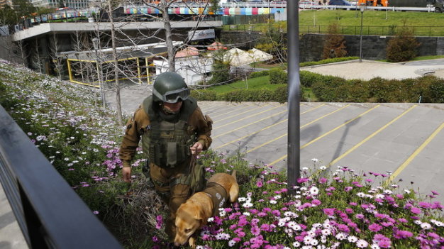 Cảnh sát đang dùng chó nghiệp vụ để kiểm tra xem còn bom hay không ở khu vực vừa xảy ra nổ bom tự chế ở ga xe điện ổ Santiago - Ảnh: Reuters
