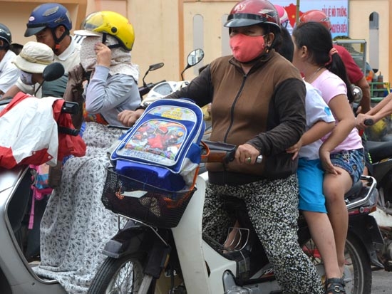 Phụ huynh chở ba, học sinh không đội mũ bảo hiểm khi ngồi trên xe máy là hình ảnh dễ thấy khi tan trường.