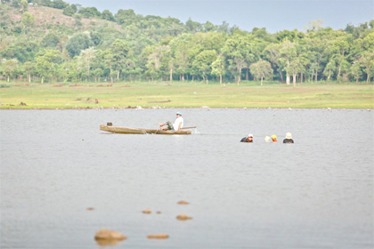   Người dân bơi thuyền gỗ mưu sinh trên hồ Ea Kao - Ảnh: Tiến Thành
